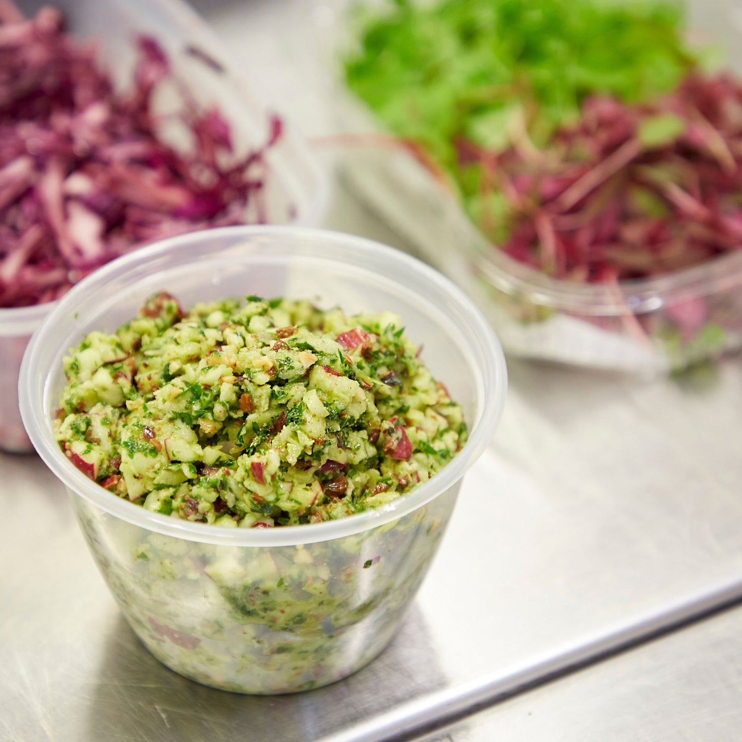Three small tubs with red cabbage, green herbs and chopped vegetables