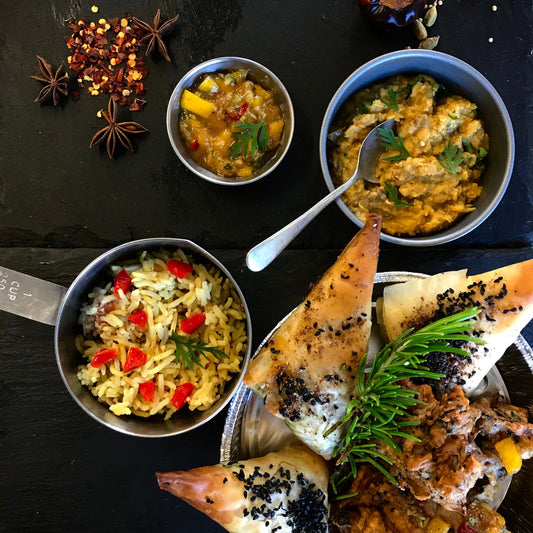 Indian street food of samosas, rice, dahl set out in little dishes