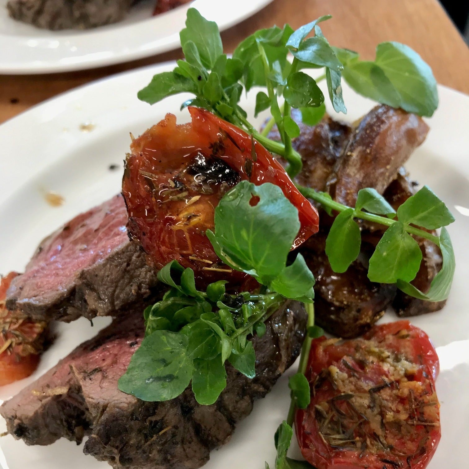 Steak on a plate with sun dried tomato and watercress