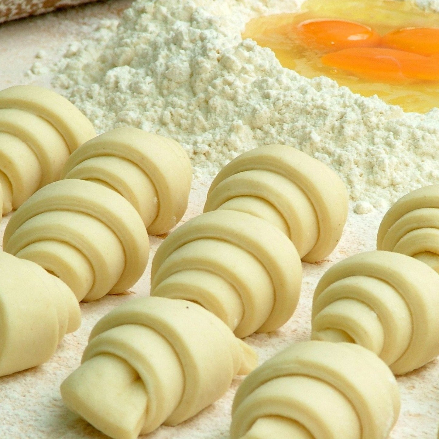 Croisants ready to bake, flour with eggs in a well