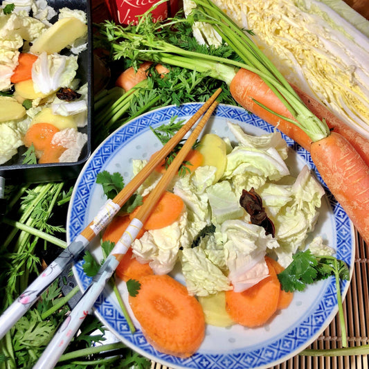 Assorted vegetables on a plate with chopsticks, including carrots, cabbage, and celery.