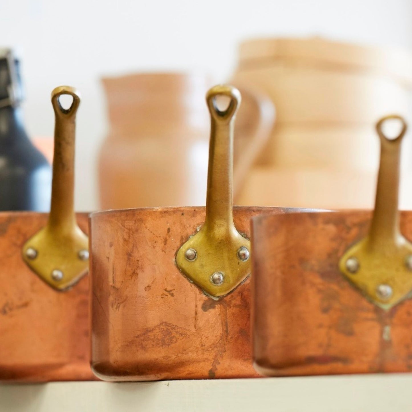 Three copper pans lined up on a shelf