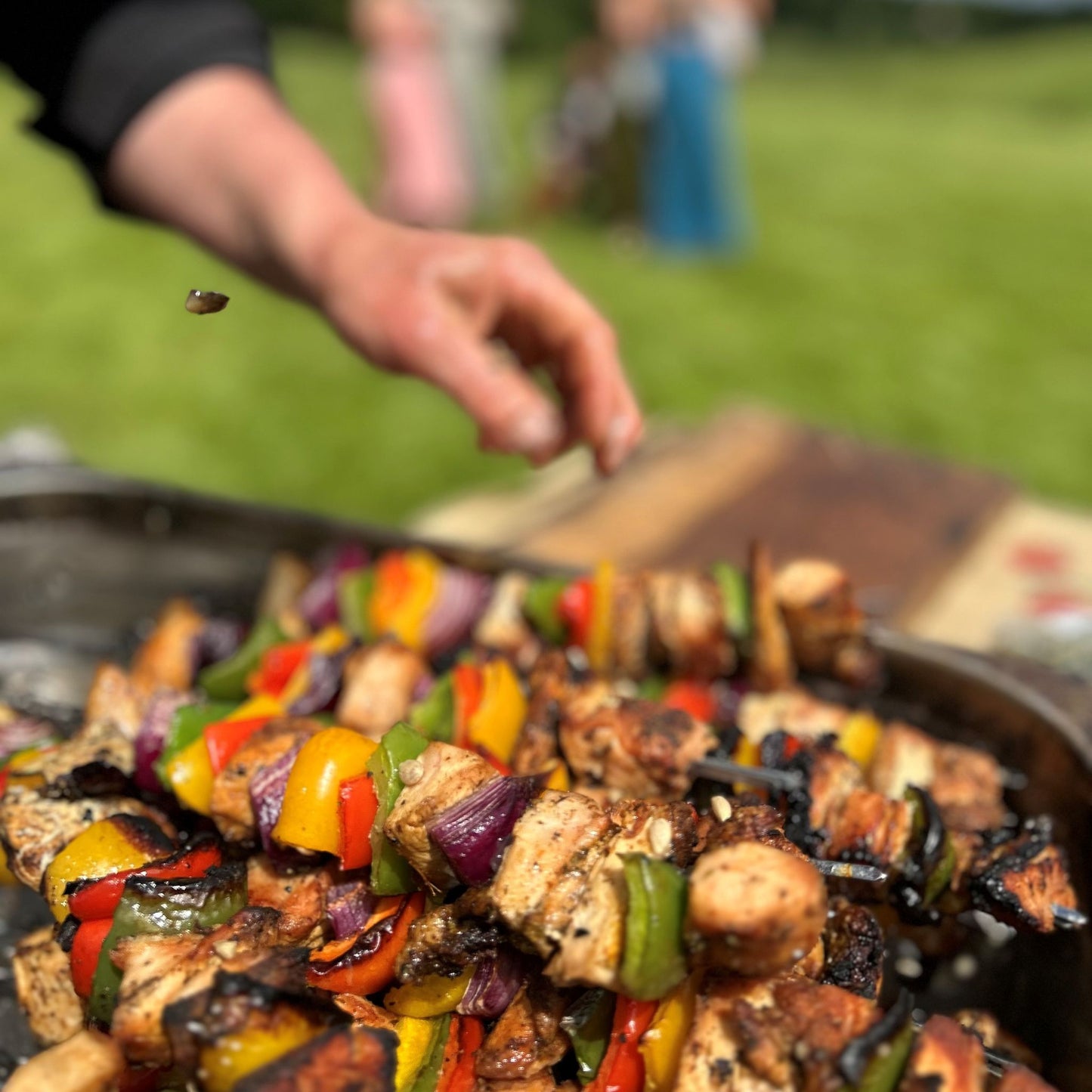 Chicken, pepper and onions on skewers with man's hand over them