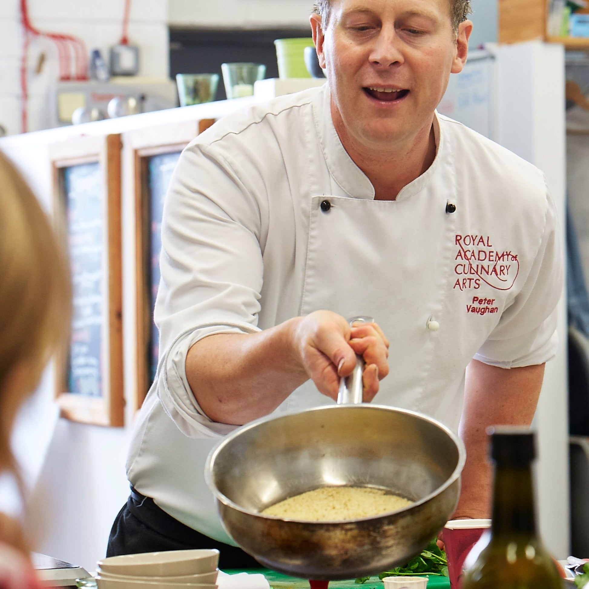 Chef Peter Vaughan making Moroccan cous cous & showing a pan to students
