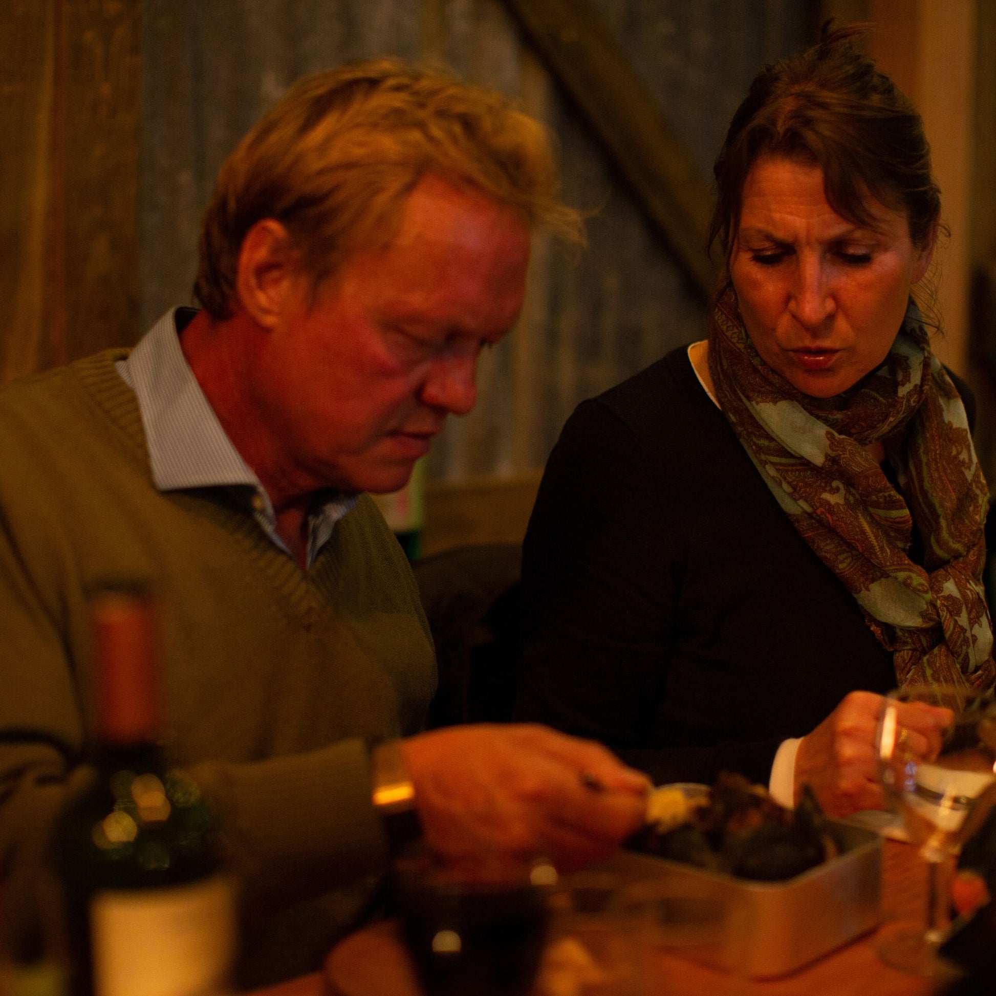 A man sharing food with a woman at a table in the barn
