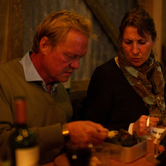 A man sharing food with a woman at a table in the barn
