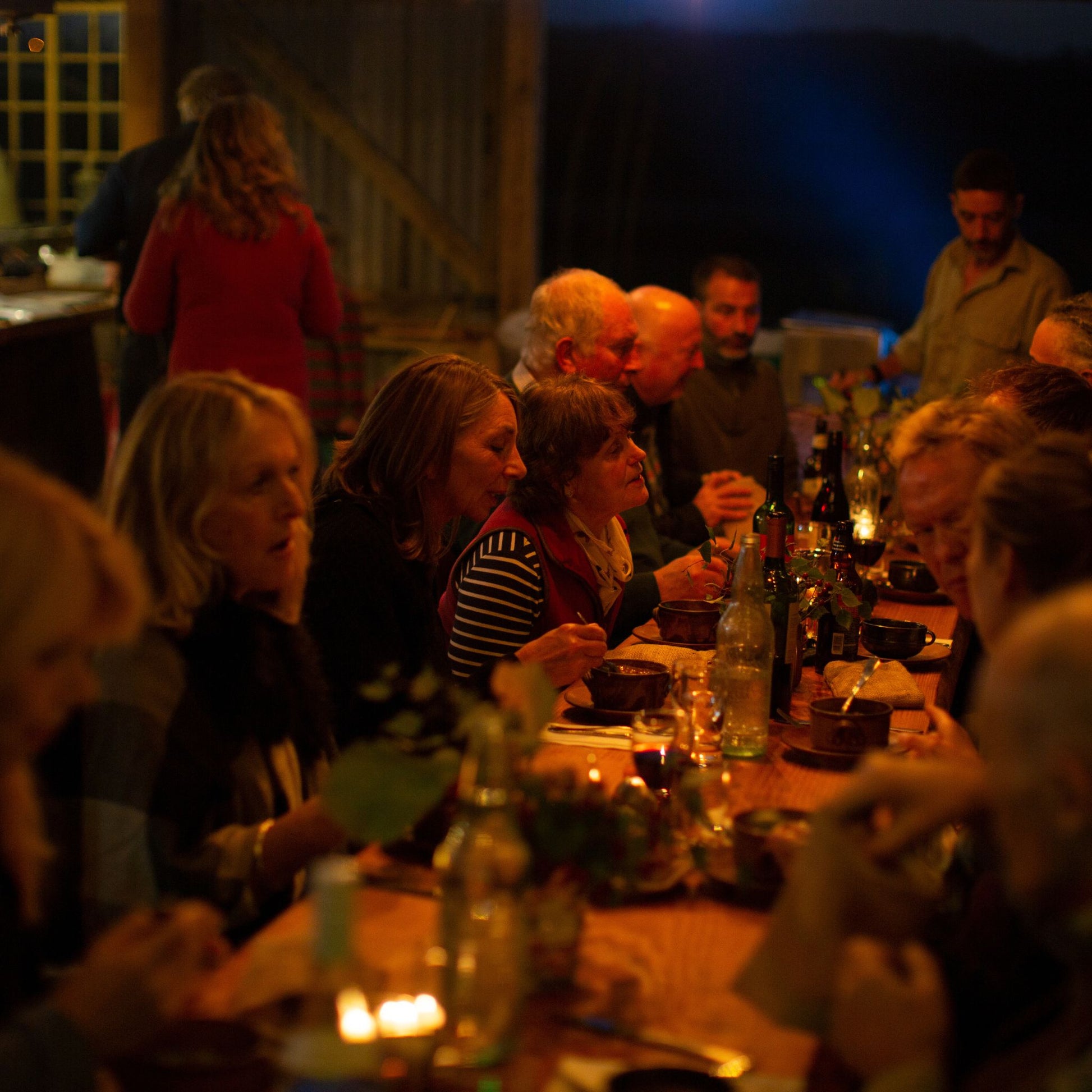 Men and women sitting at a long table sharing food