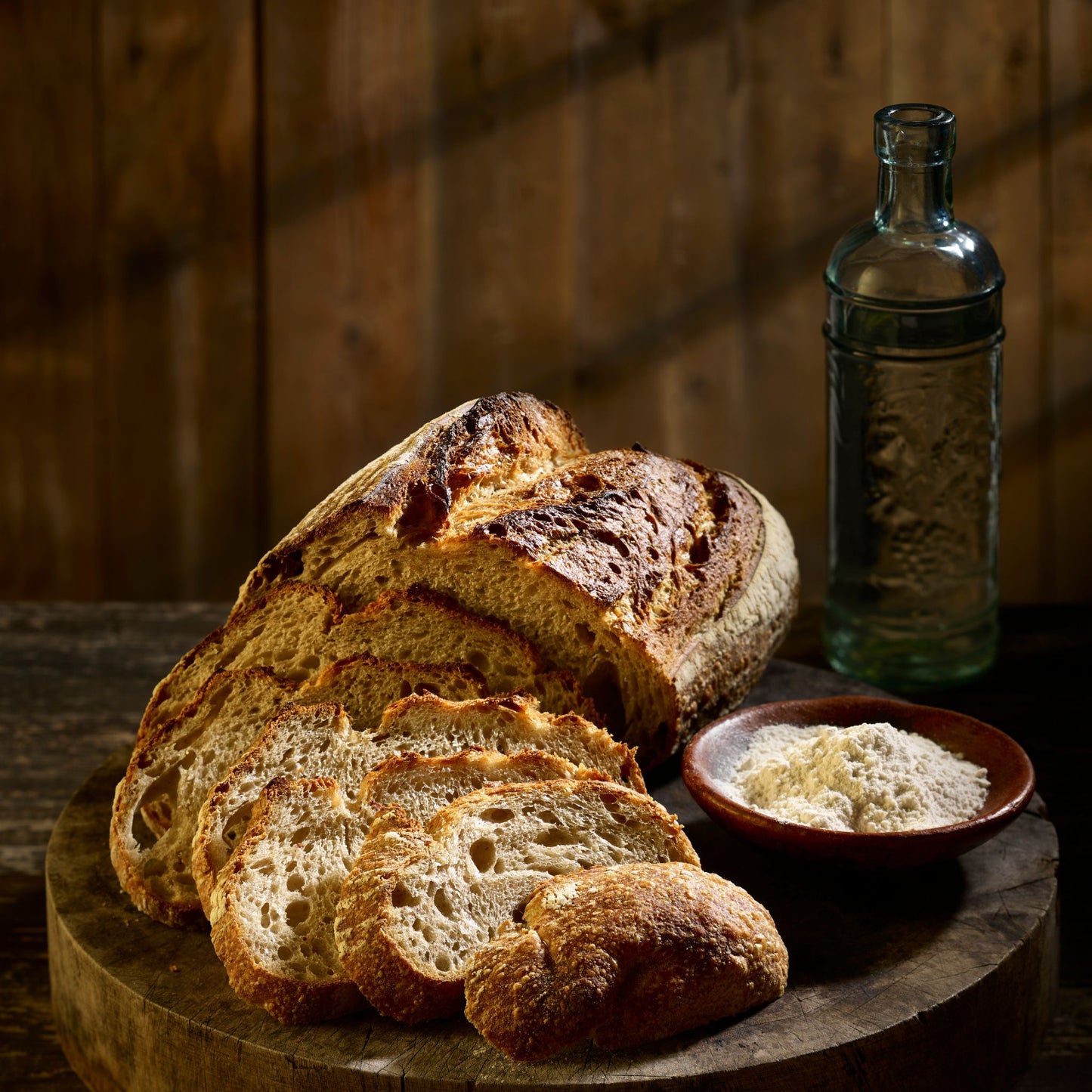 Sourdough bread on a big wooden board, flour and water